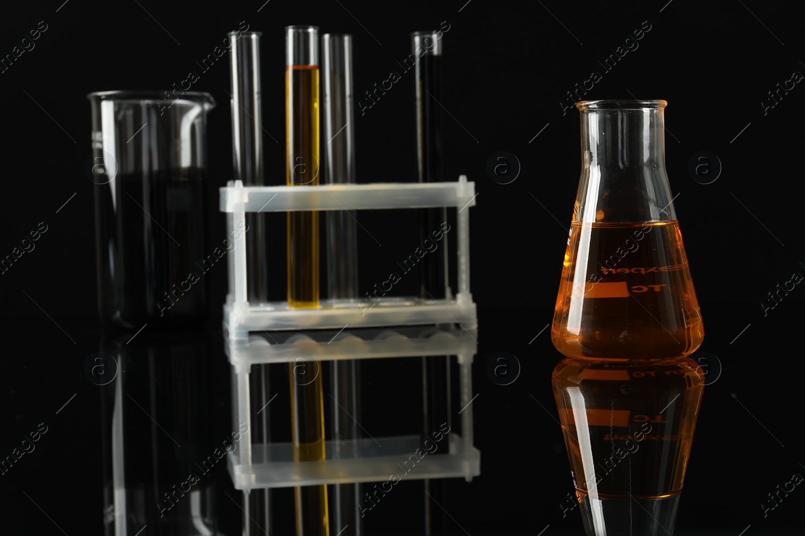 Photo of Laboratory glassware with different types of oil on black background, closeup