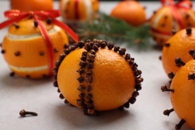 Photo of Pomander balls made of tangerines with cloves on grey table, closeup