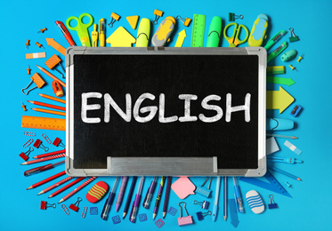 Image of Chalkboard with word ENGLISH and different stationery on color background, flat lay