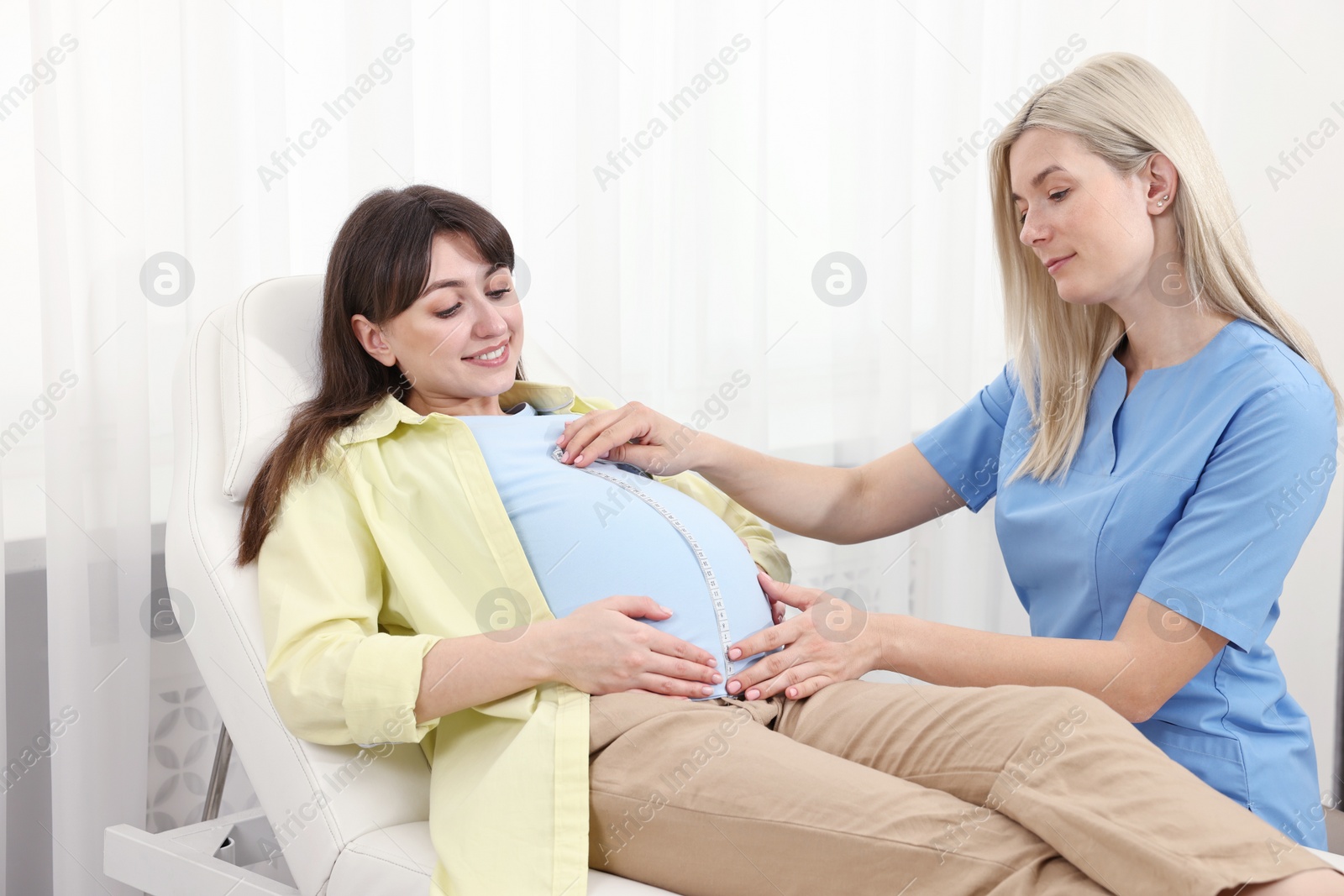 Photo of Pregnancy checkup. Doctor measuring patient's tummy in clinic