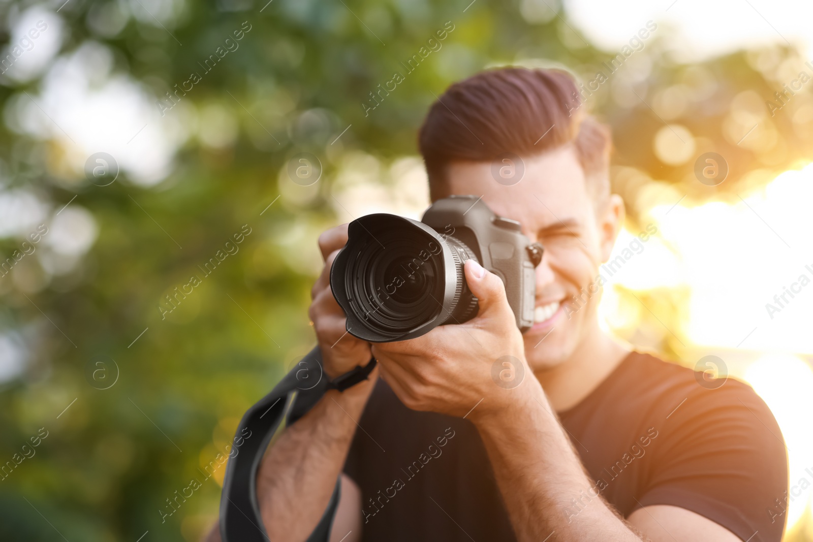 Photo of Photographer taking picture with professional camera in countryside, focus on lens