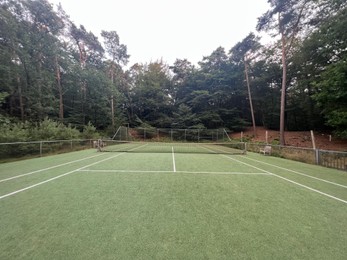 Photo of Tennis court with green grass and net outdoors