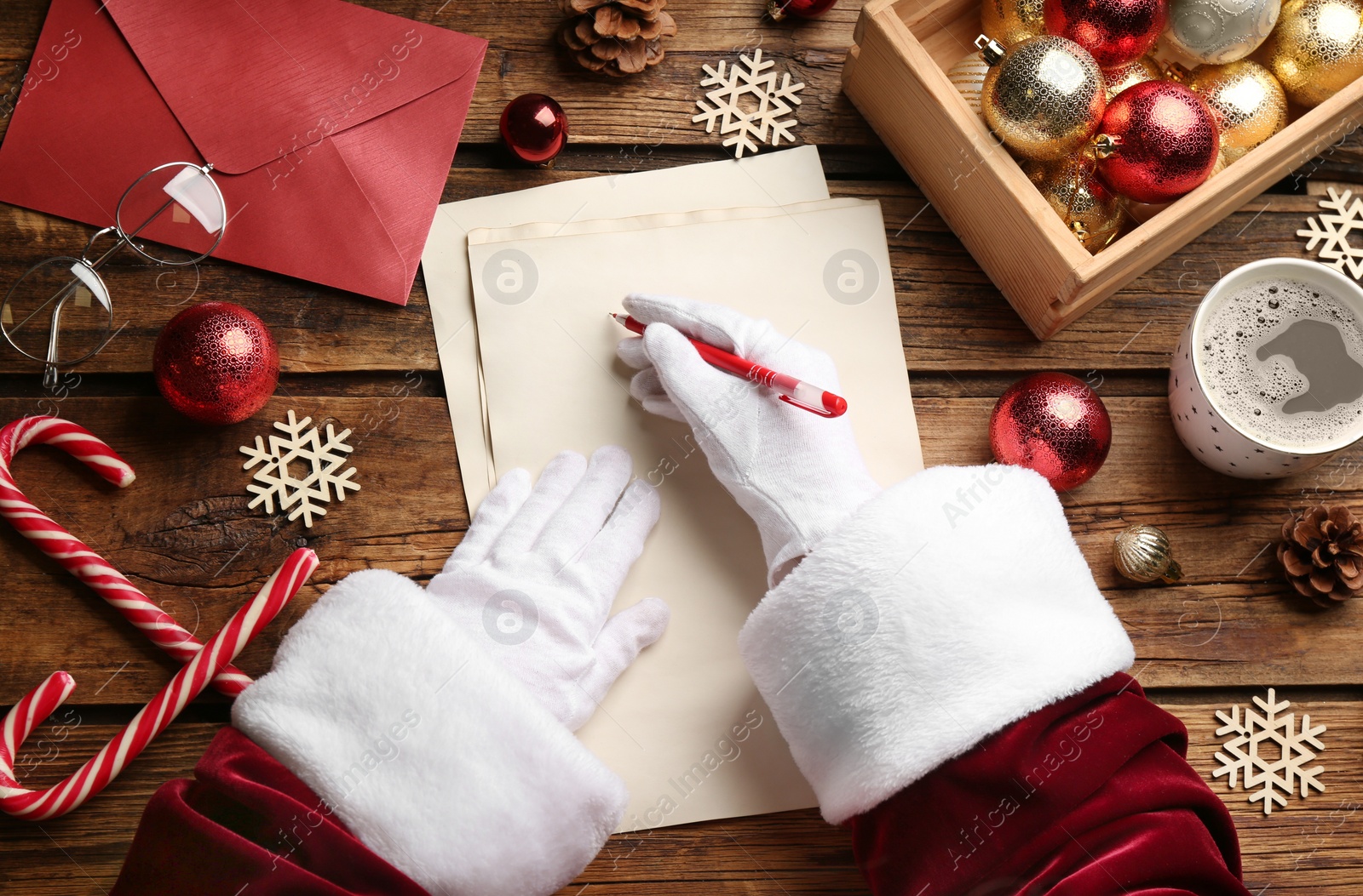 Photo of Top view of Santa writing letter at wooden table, closeup