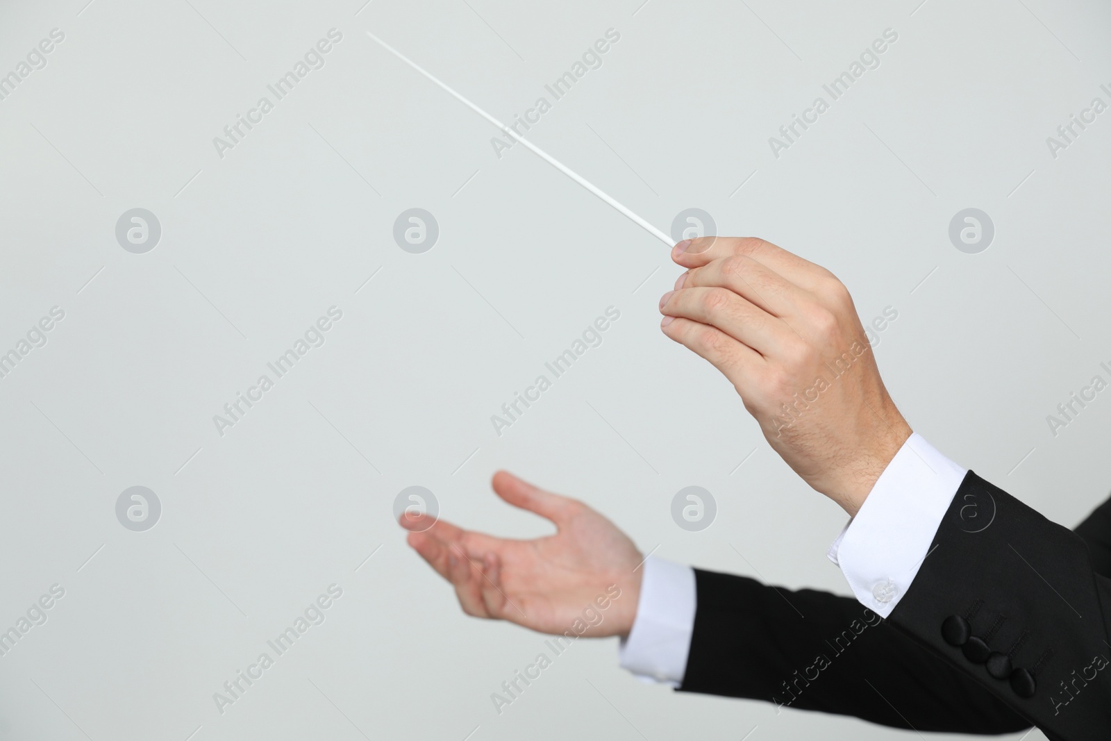 Photo of Professional conductor with baton on light grey background, closeup. Space for text