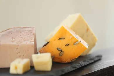 Photo of Different types of delicious cheeses on slate plate, closeup