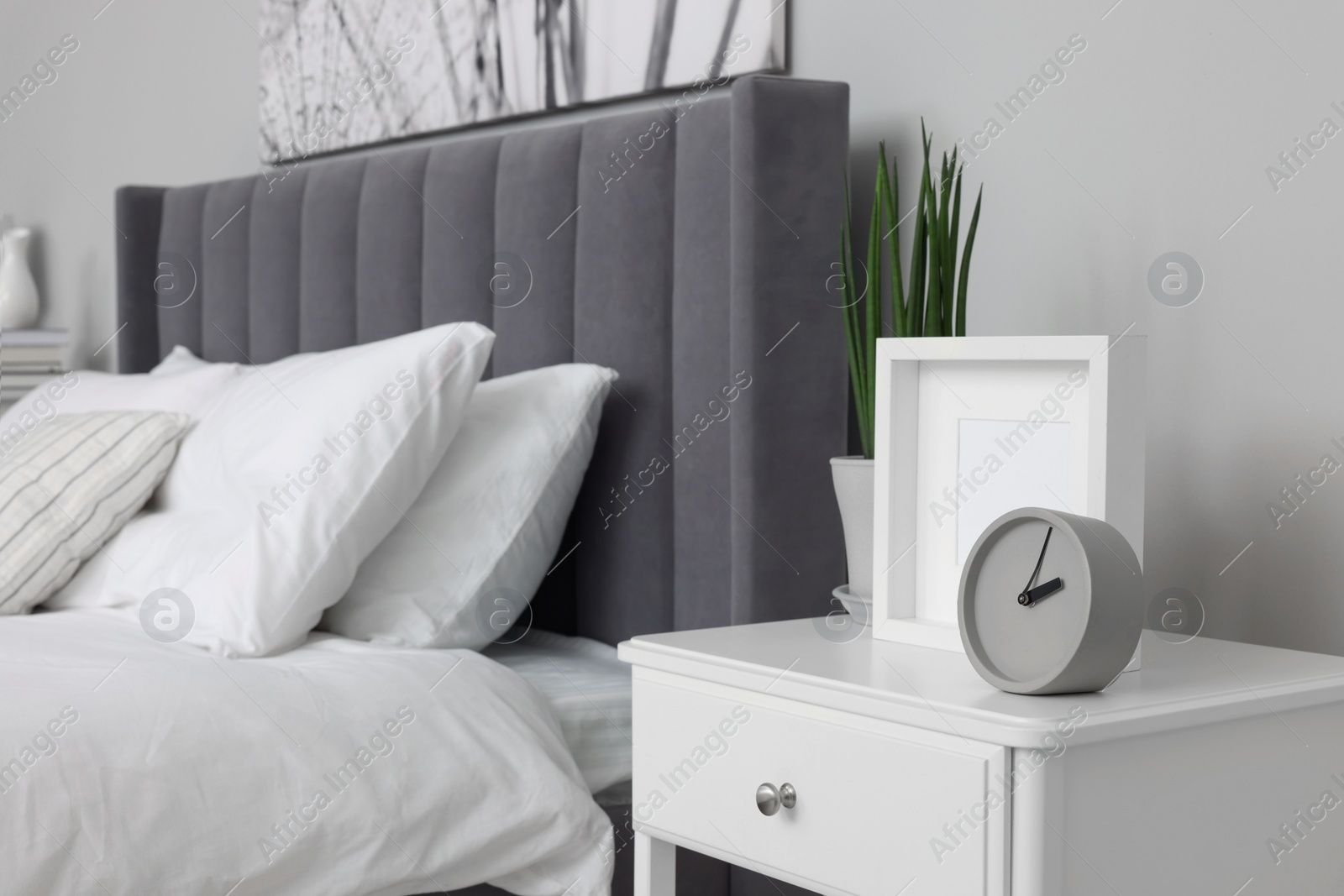 Photo of Large comfortable bed and bedside table in room. Stylish interior