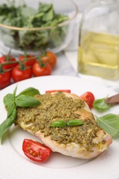 Photo of Delicious chicken breast with pesto sauce, tomatoes and basil on table
