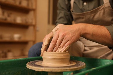 Clay crafting. Man making bowl on potter's wheel indoors, closeup