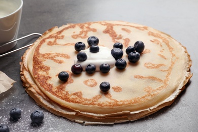 Thin pancakes with cream and berries on table