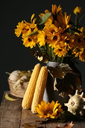 Photo of Beautiful autumn bouquet, corn cobs and small pumpkins on wooden table against dark grey background