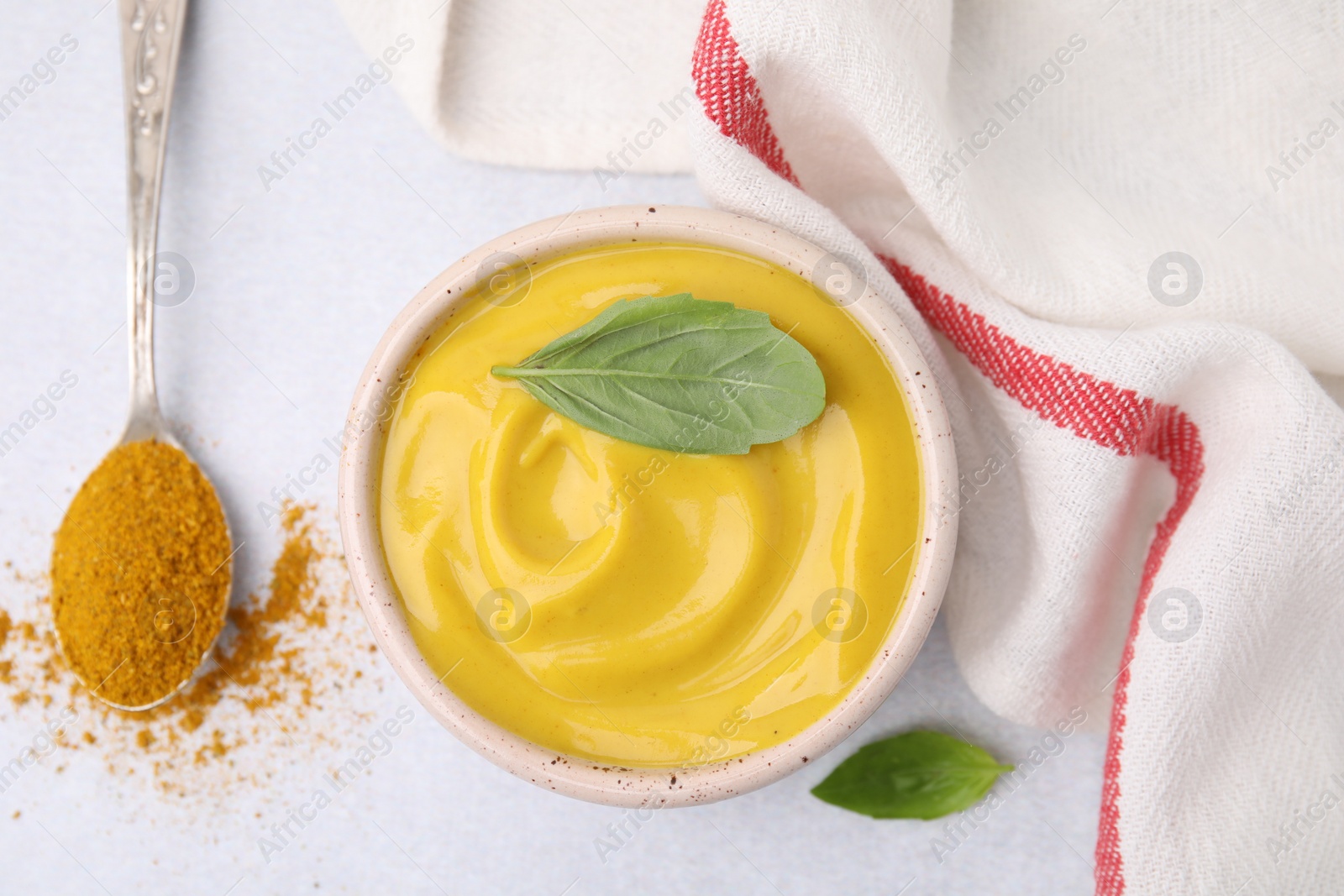 Photo of Tasty curry sauce, powder and basil leaves on light table, flat lay