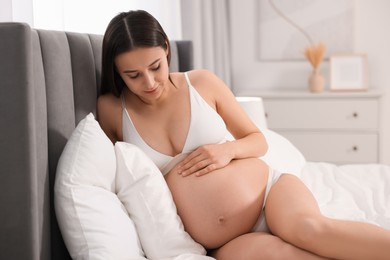 Beautiful pregnant woman in stylish comfortable underwear on bed at home