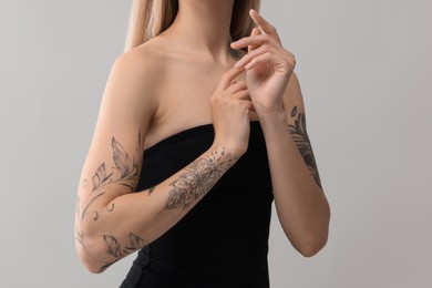 Photo of Woman with cool tattoos on light background, closeup