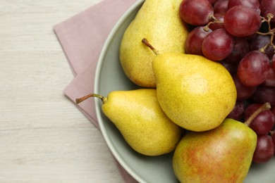 Fresh ripe pears and grapes on light wooden table, top view. Space for text