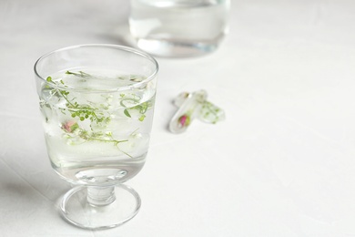 Photo of Glass of water and floral ice cubes on table. Space for text