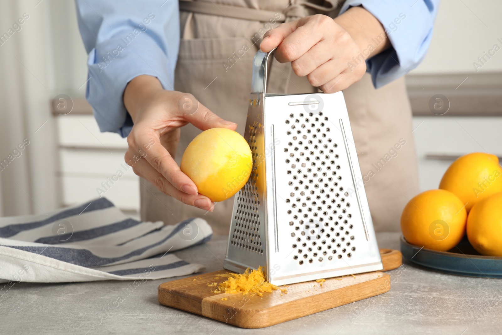 Photo of Woman zesting lemon at table indoors, closeup