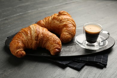 Photo of Delicious fresh croissants and cup of coffee on gray table