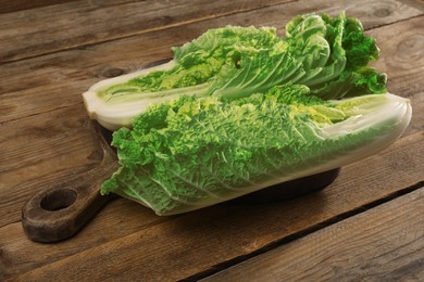 Photo of Halves of fresh ripe Chinese cabbage on wooden table