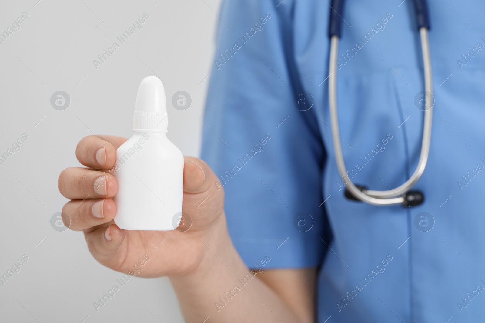 Photo of Doctor holding nasal spray on white background, closeup