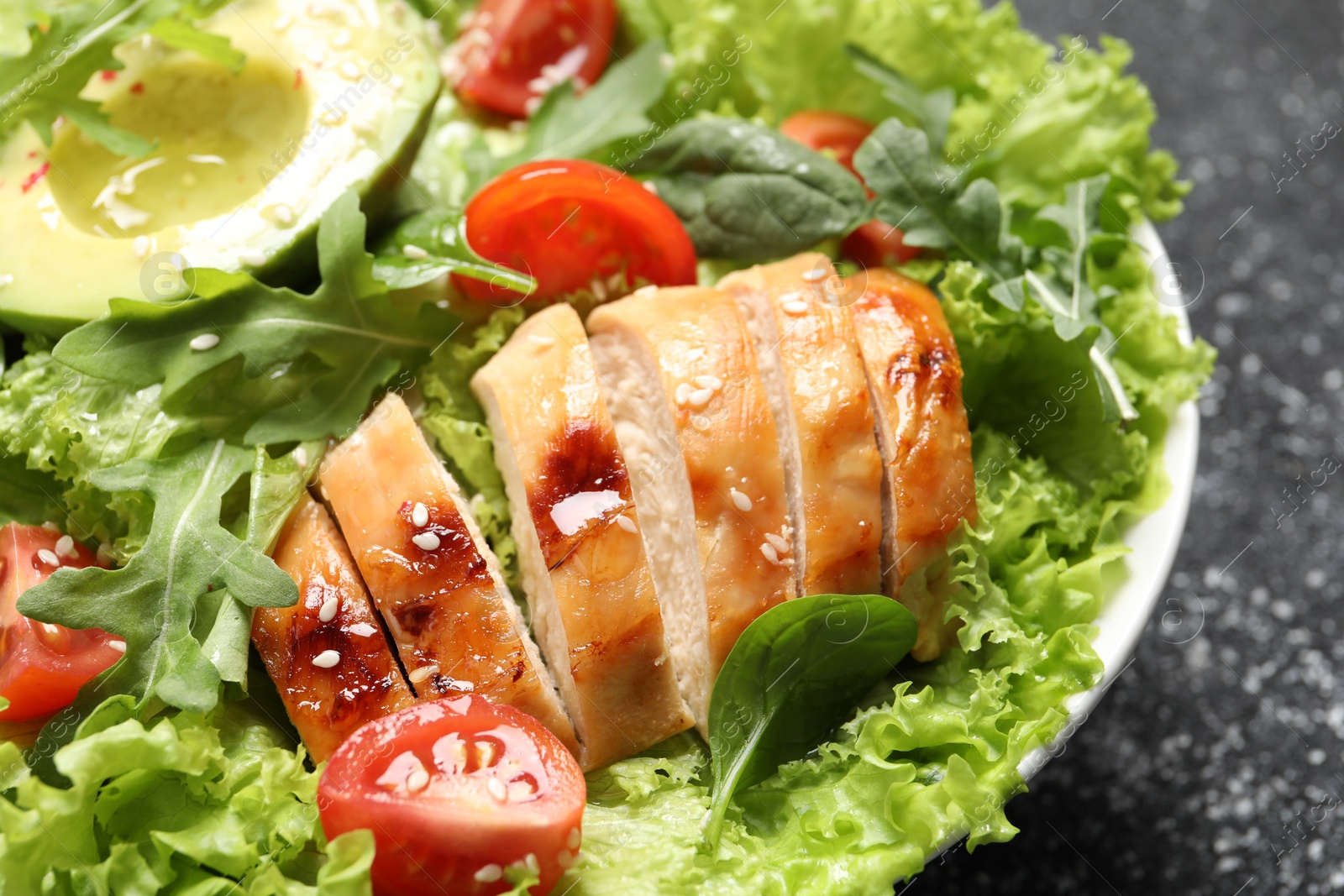 Photo of Delicious salad with chicken, cherry tomato and avocado on table, closeup