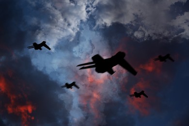 Image of Silhouettes of jet fighters in cloudy sky at night