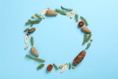 Photo of Frame of pinecones and fir branches on light blue background, flat lay. Space for text