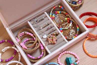 Photo of Jewelry box with stylish bracelets and other accessories on wooden table, above view