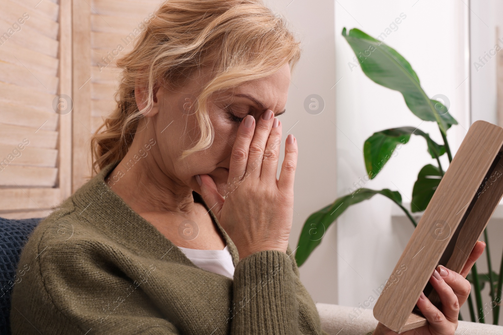 Photo of Upset middle aged woman with photo frame at home. Loneliness concept