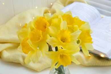 Photo of Beautiful yellow daffodils in vase indoors, closeup view