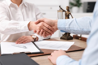 Photo of Lawyers shaking hands at table in office, closeup