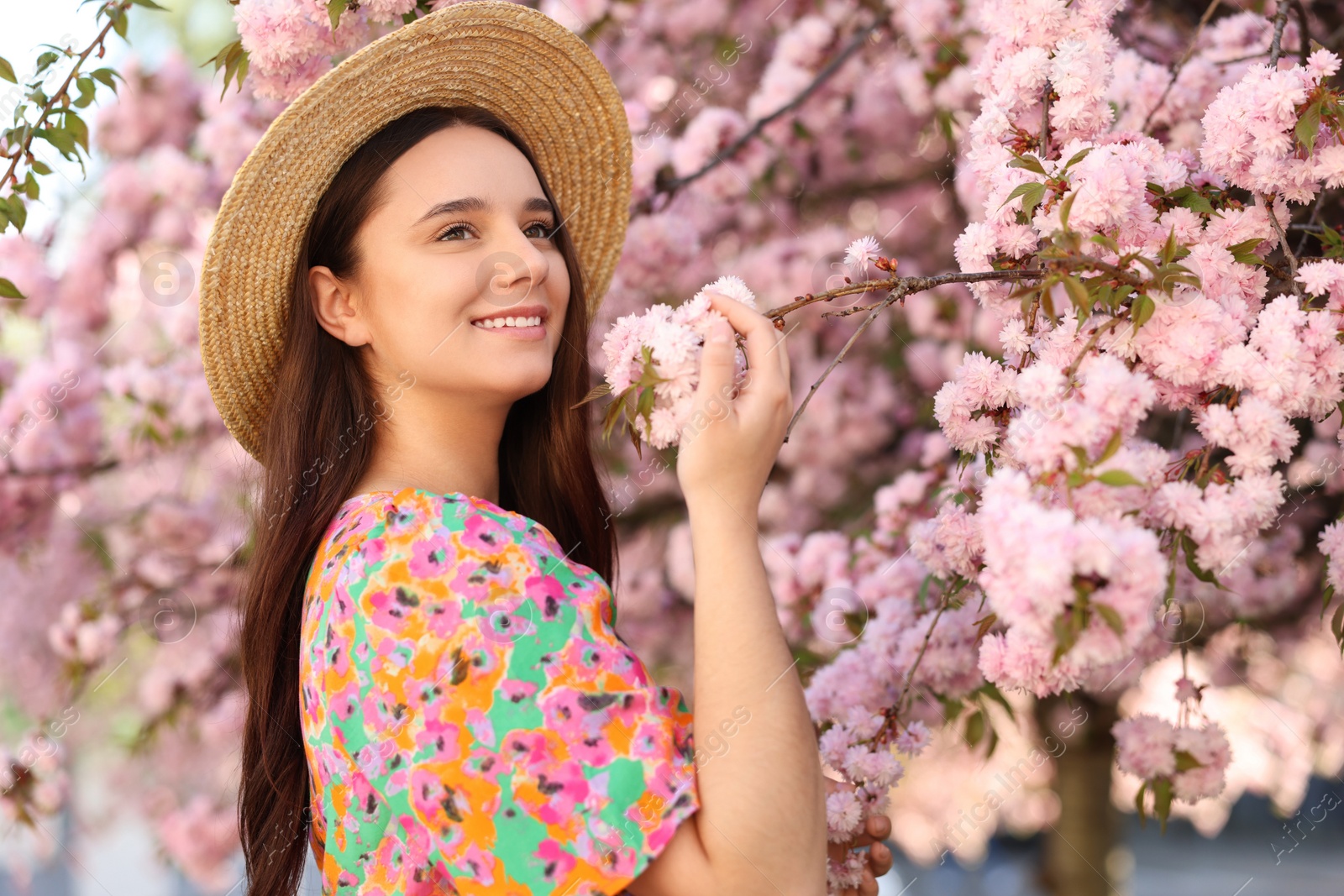 Photo of Beautiful woman in straw hat near blossoming tree on spring day