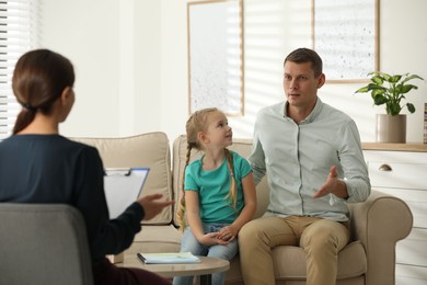 Little girl and her father on appointment with child psychotherapist indoors
