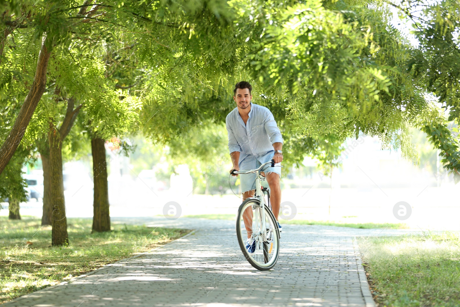 Photo of Handsome young hipster man riding bicycle in park