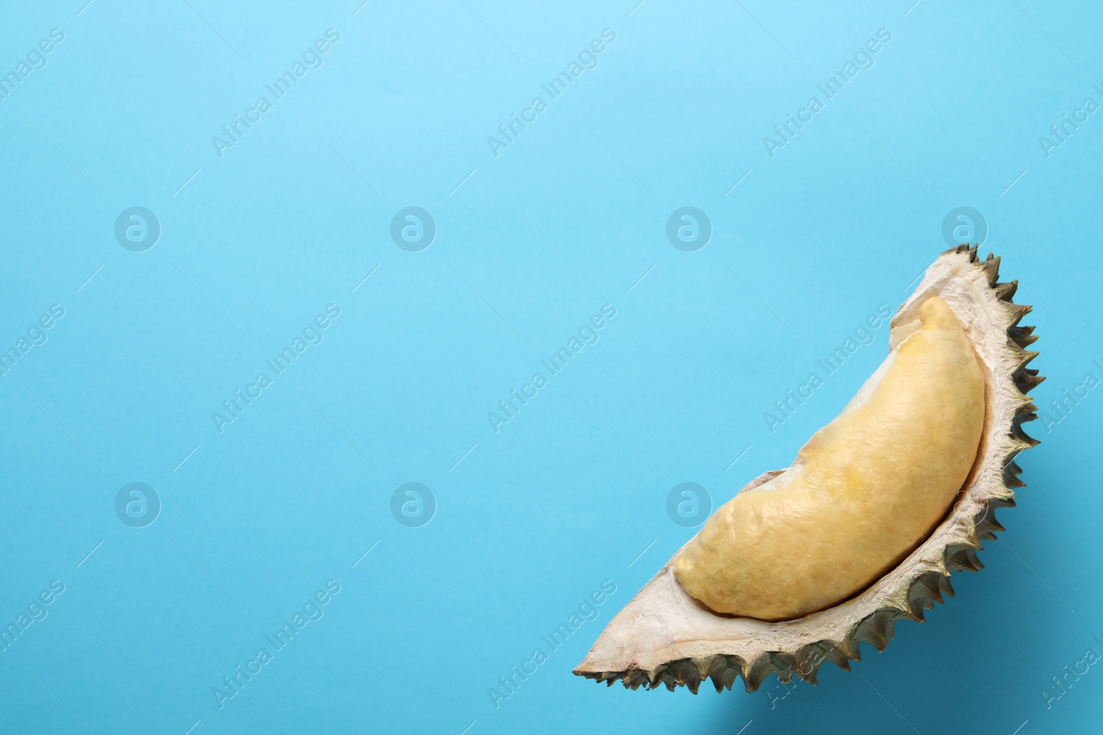 Photo of Piece of fresh ripe durian on light blue background, top view. Space for text