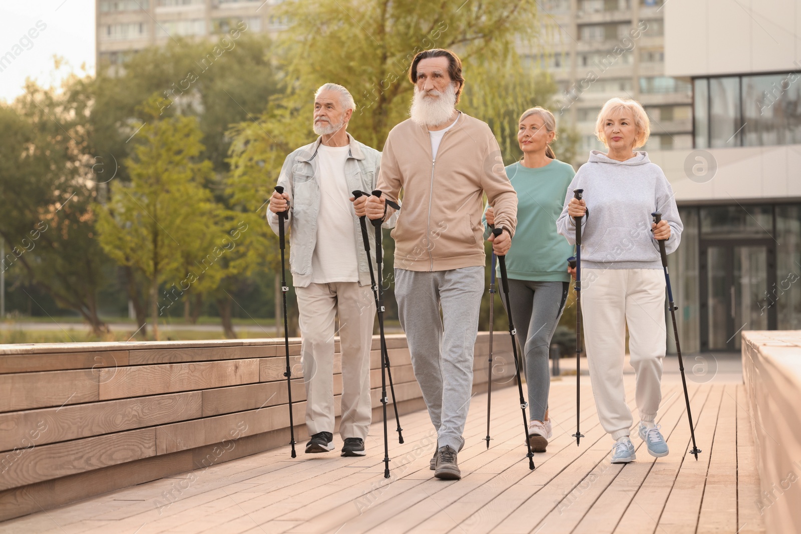 Photo of Group of senior people performing Nordic walking outdoors. Low angle view