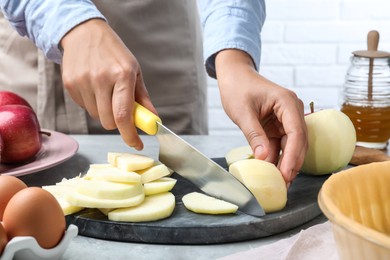 Photo of Woman cutting apple at grey table, closeup. Baking pie
