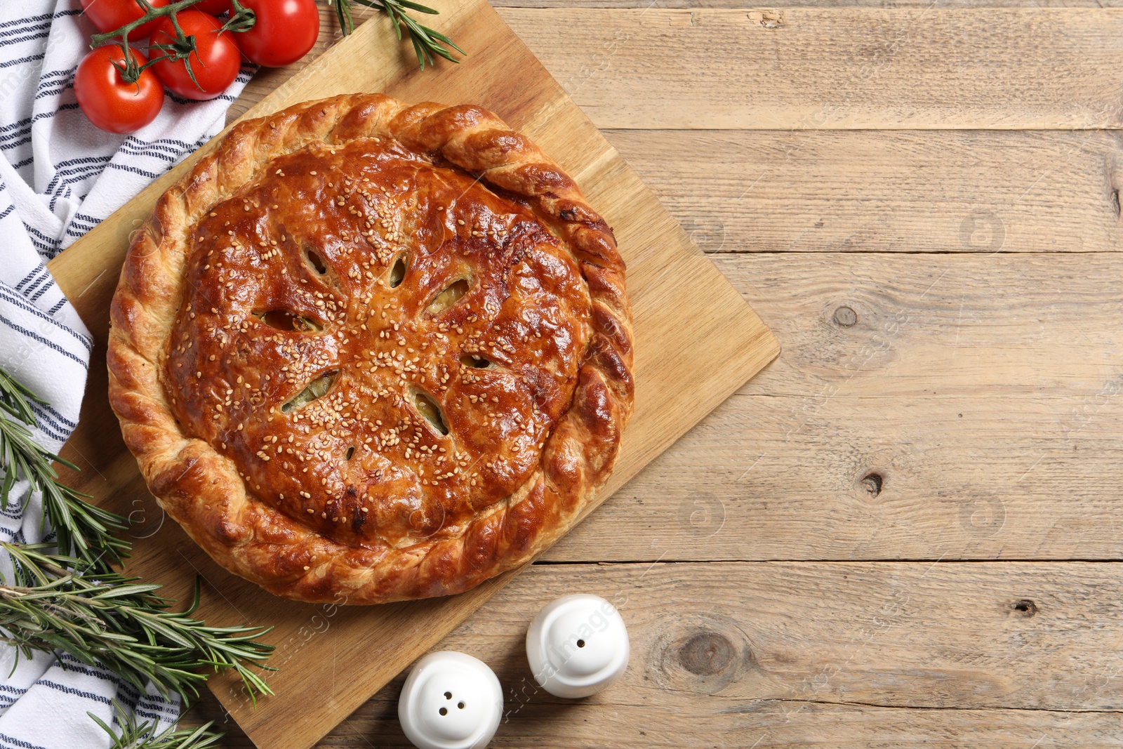 Photo of Tasty homemade pie, rosemary and tomatoes on wooden table, flat lay. Space for text