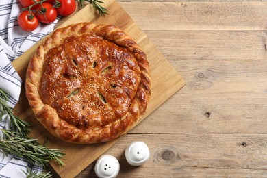 Photo of Tasty homemade pie, rosemary and tomatoes on wooden table, flat lay. Space for text