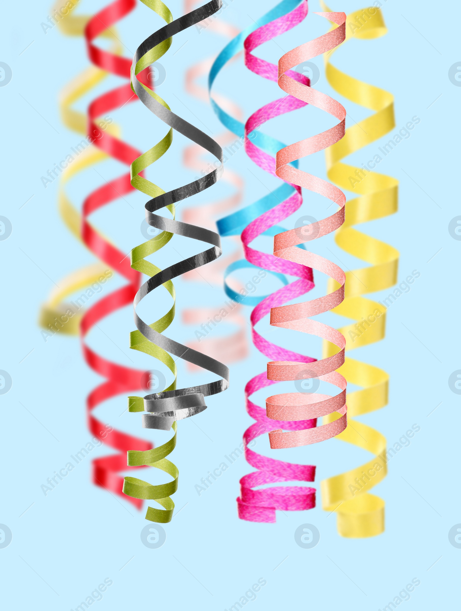 Image of Many serpentine streamers on pale light blue background. Party decor