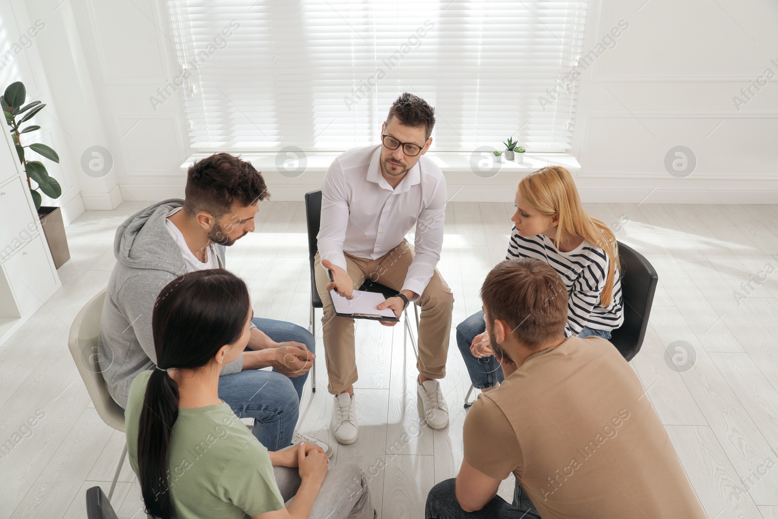 Photo of Psychotherapist working with group of drug addicted people at therapy session indoors