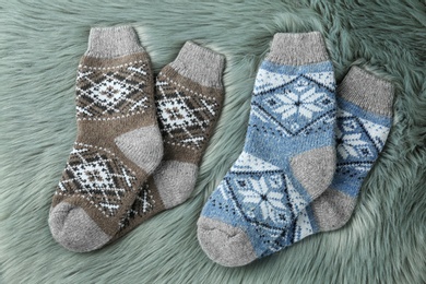 Photo of Knitted socks on grey faux fur, flat lay