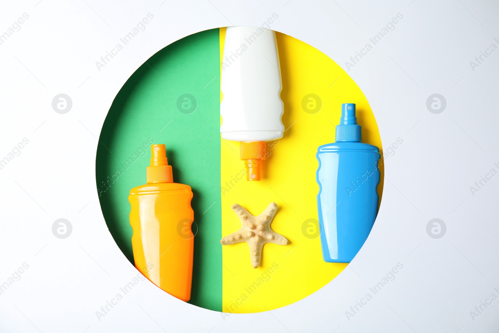 Photo of Bottles with sun protection products and starfish in round frame on color background, top view