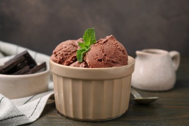Photo of Bowl of tasty chocolate ice cream on wooden table, closeup