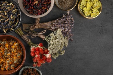 Photo of Many different dry herbs and flowers on dark grey table, flat lay. Space for text