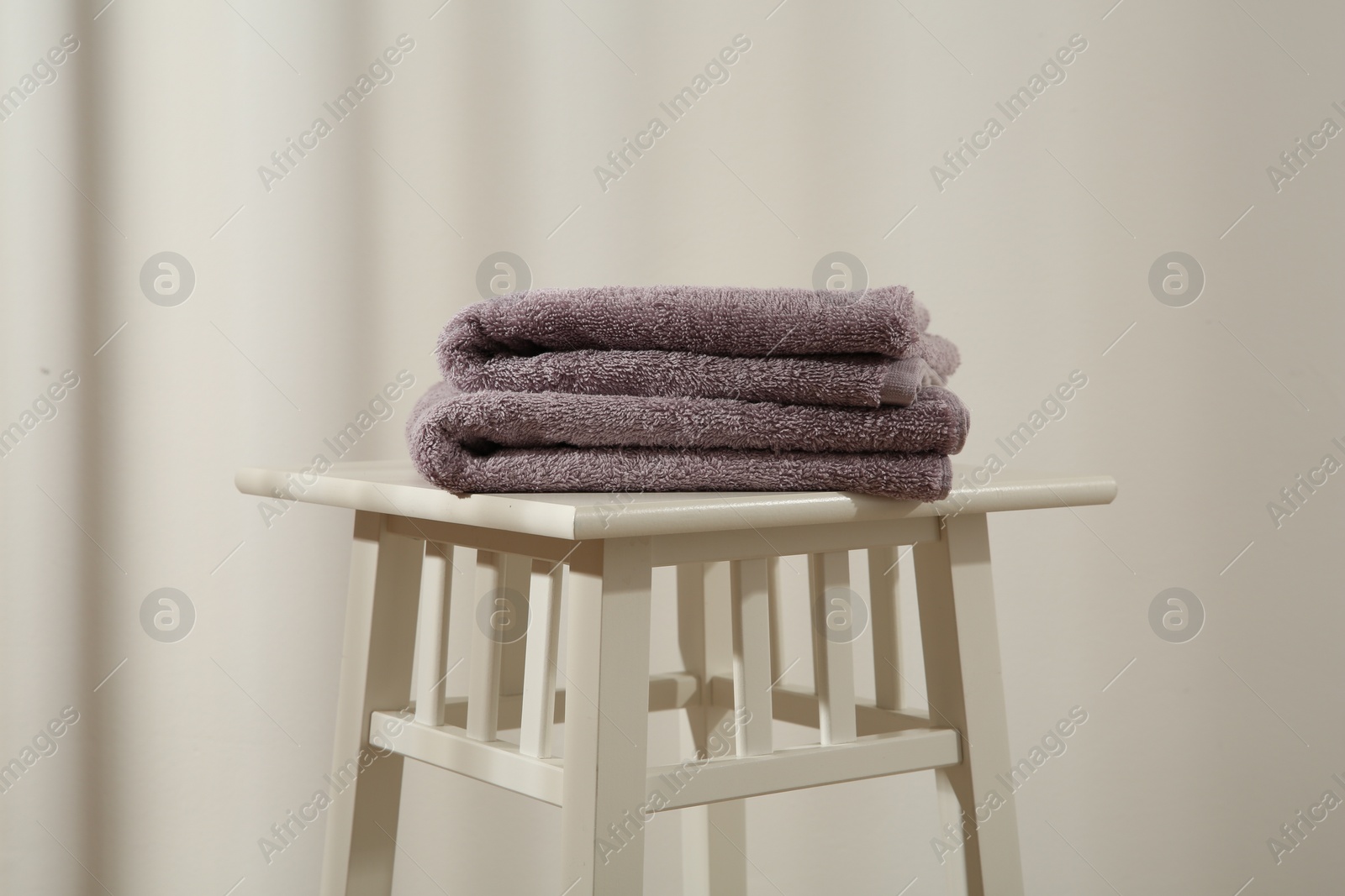 Photo of Violet towels on stool against white wall