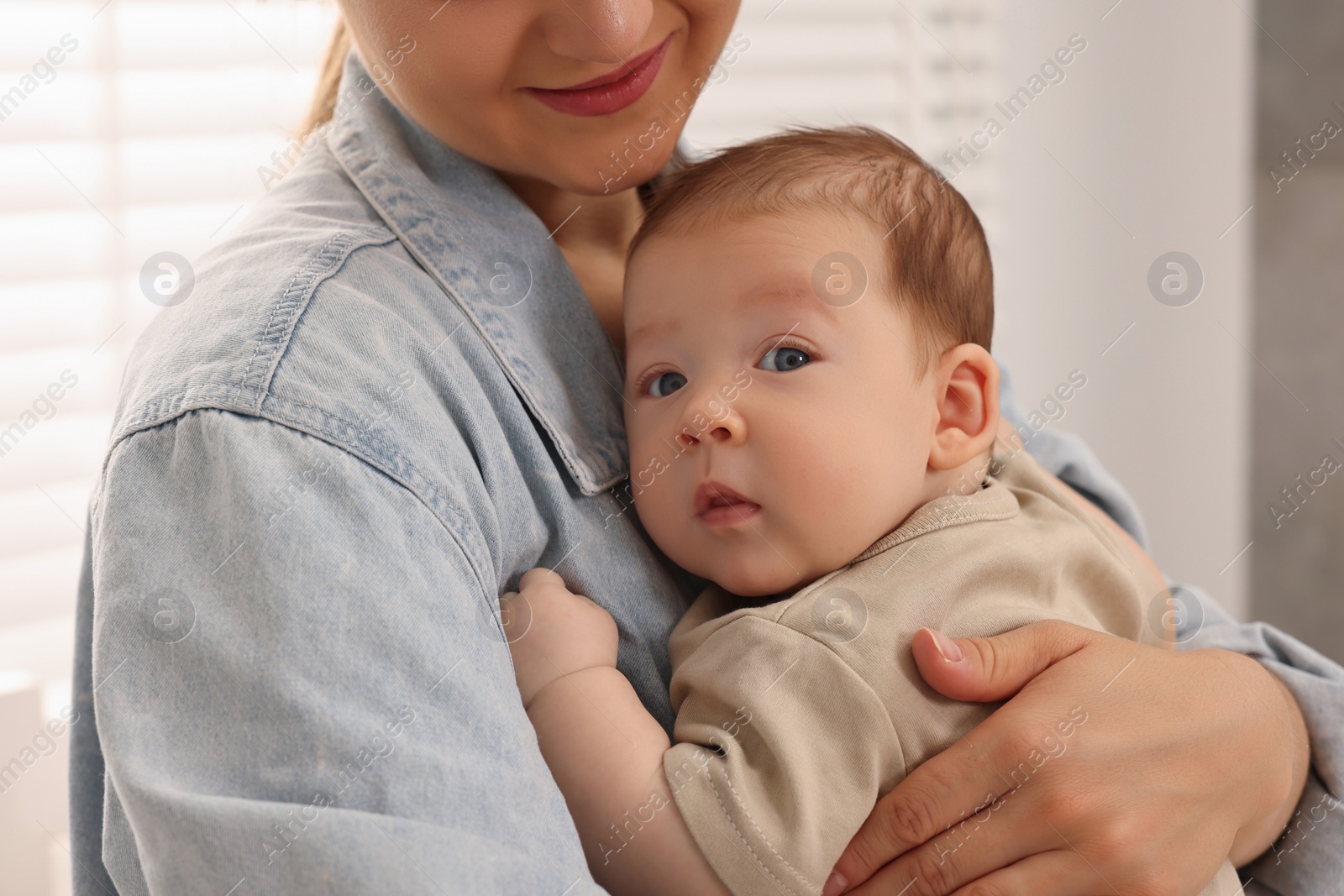 Photo of Mother holding her cute newborn baby indoors, closeup