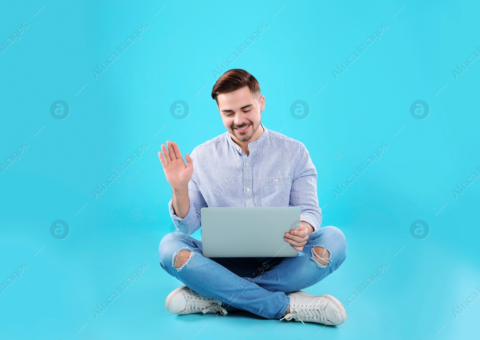 Photo of Man using laptop for video chat on color background