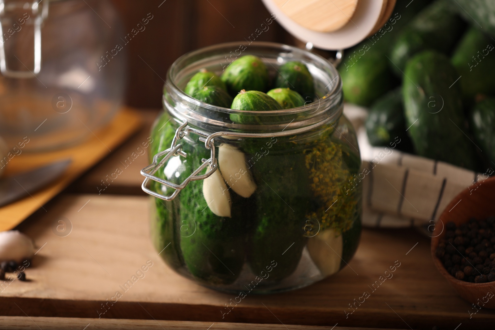 Photo of Glass jar with fresh cucumbers and other ingredients on wooden table. Canning vegetable
