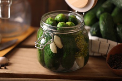 Glass jar with fresh cucumbers and other ingredients on wooden table. Canning vegetable