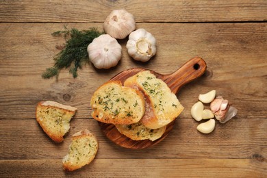 Photo of Tasty baguette with garlic and dill on wooden table, flat lay